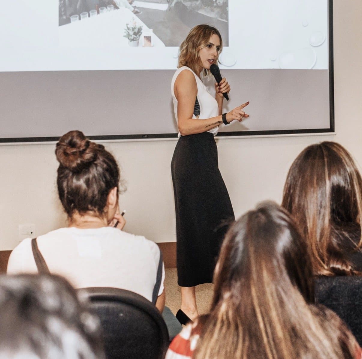 Xanda Fogaça falando ao microfone para uma plateia